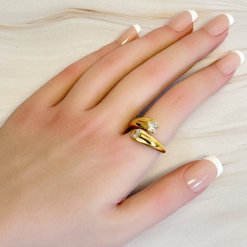 Hand wearing a gold ring with a diamond on a light background