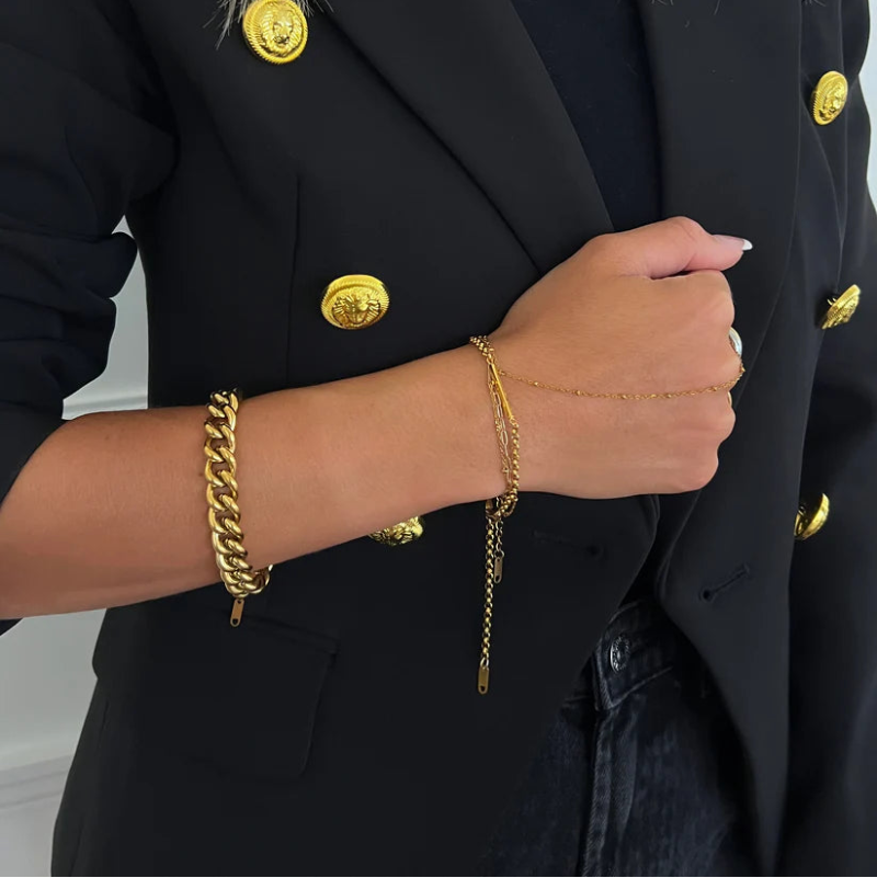 Person wearing a black blazer with gold buttons and gold jewelry.