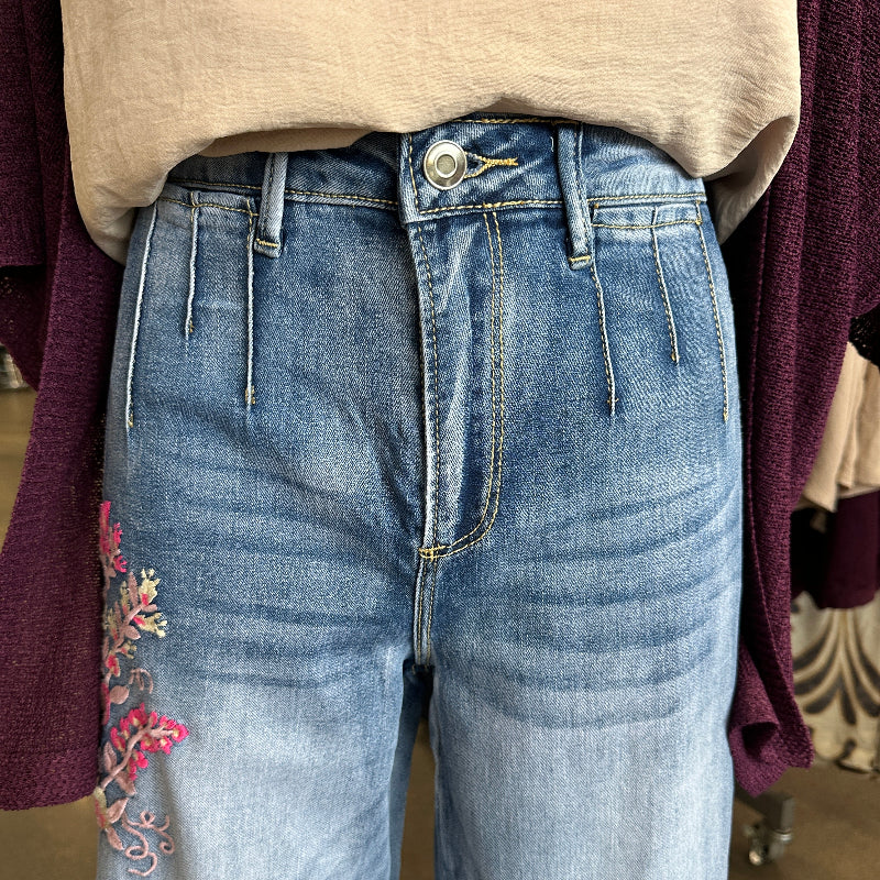 Close-up of blue jeans with floral embroidery on a blurred background