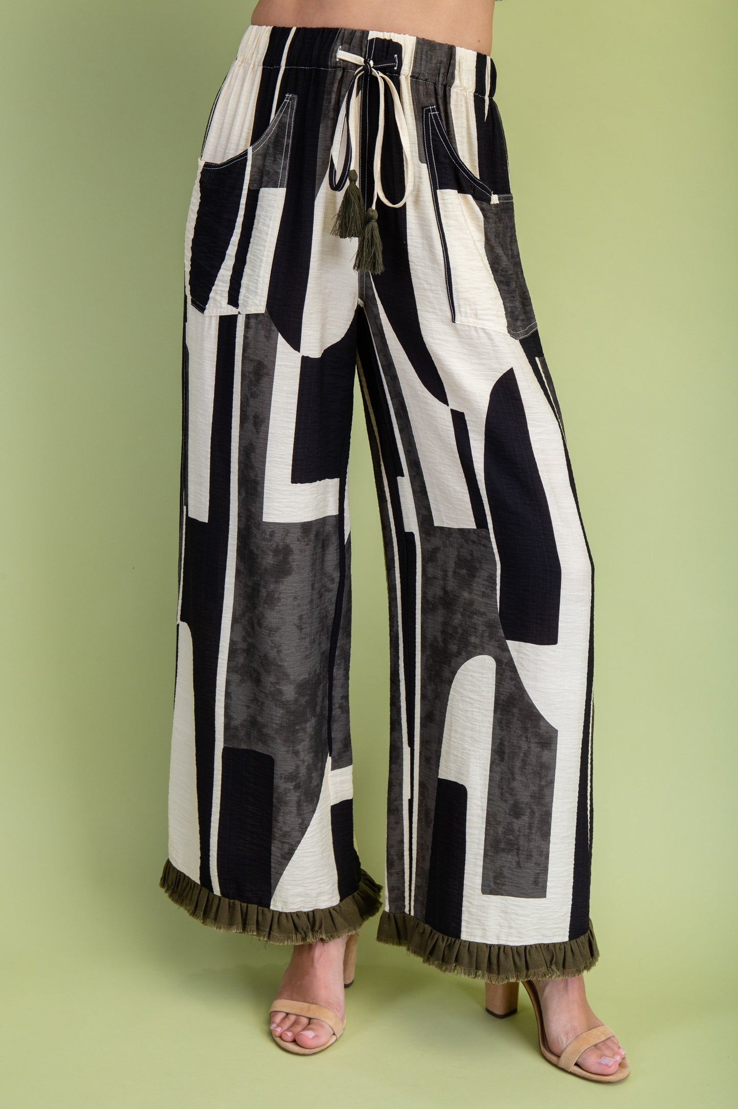Black and white geometric patterned pants on a green background
