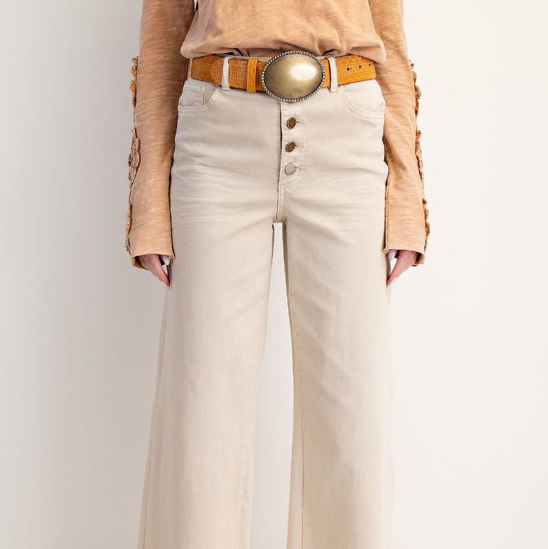 Person wearing beige shirt, white pants, and brown boots with a white background
