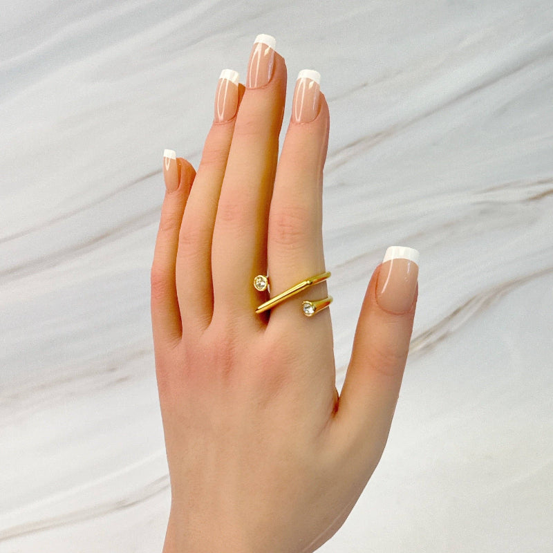 Hand wearing a gold ring with a diamond on a light background