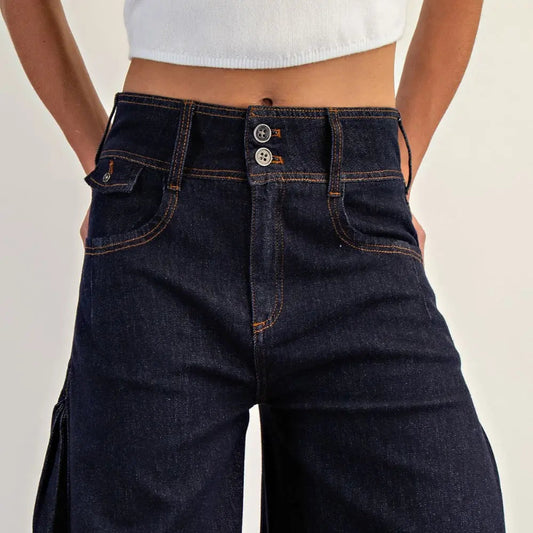 Dark blue wide-leg jeans worn by a person on a light gray background
