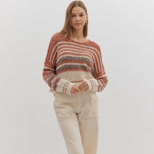 Woman wearing a striped sweater and beige pants on a white background