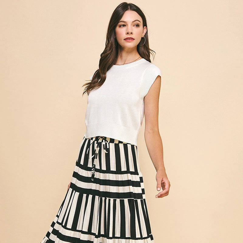 Woman wearing a white top and black and white striped skirt on a beige background