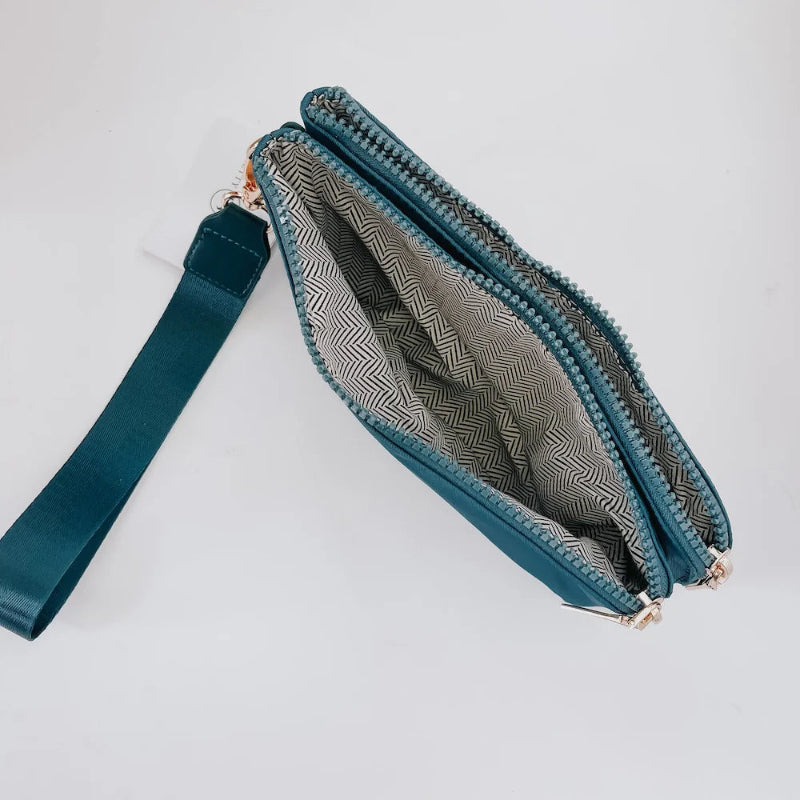 Teal clutch bag with a strap on a light gray background