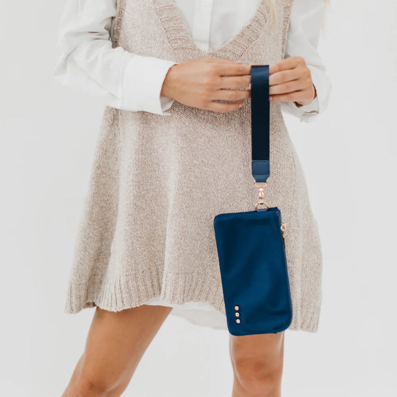 Person holding a blue crossbody bag against a plain background