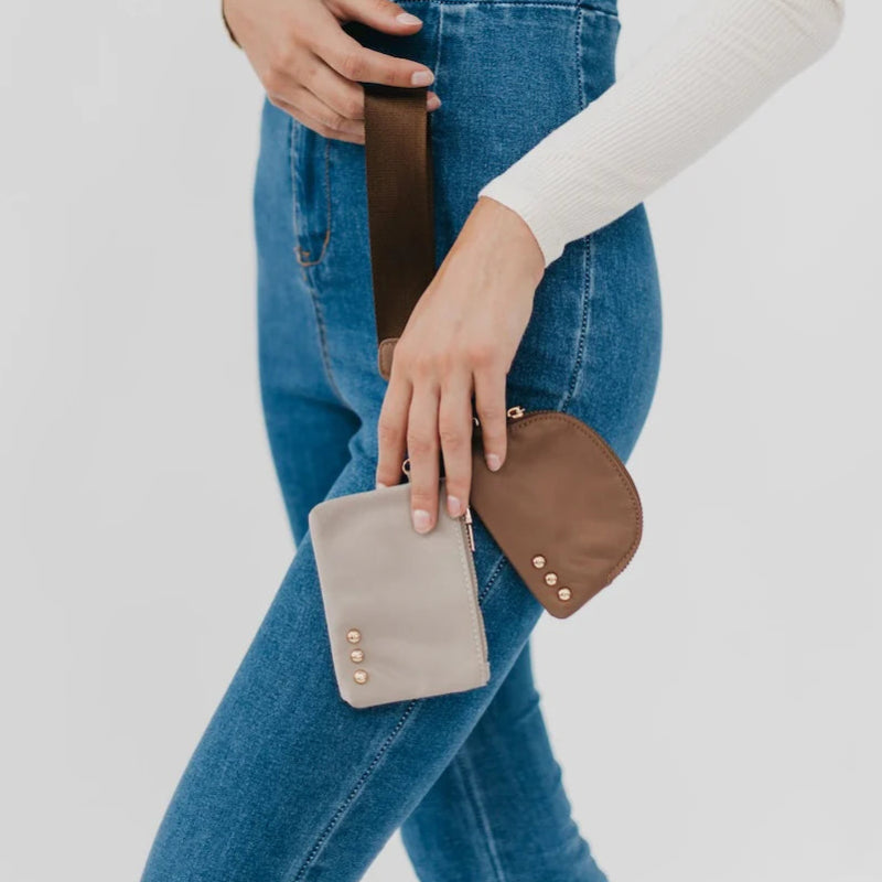 Person holding two small leather bags against a plain background