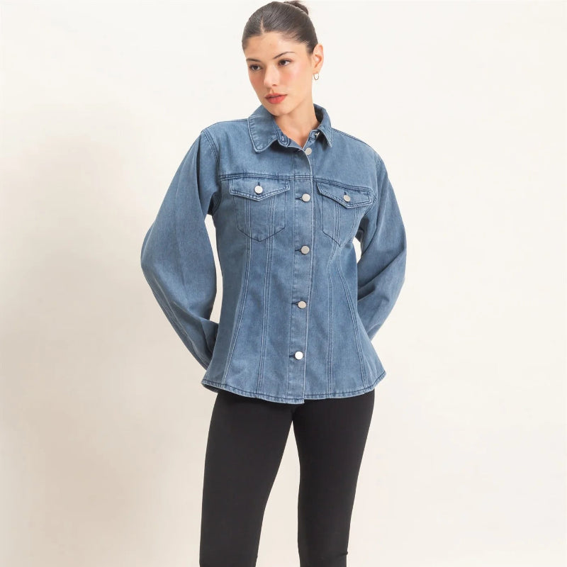 A woman modeling a light blue denim button-up shirt with front chest pockets, paired with black capri leggings and black heeled sandals, against a plain light beige studio background.