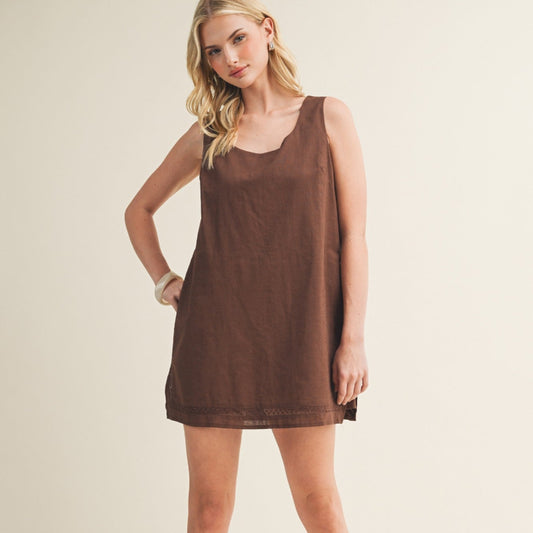 Woman wearing a brown sleeveless dress on a plain background