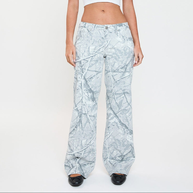 Woman wearing a white crop top and light blue patterned pants on a white background