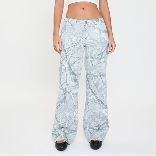 Woman wearing a white crop top and light blue patterned pants on a white background