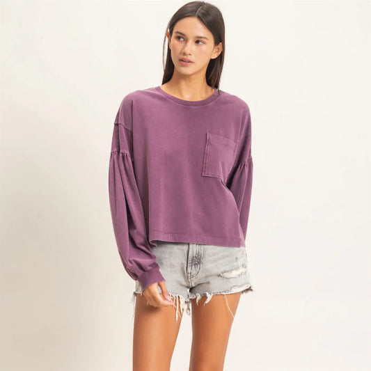 Woman wearing a purple long-sleeve shirt and denim shorts on a white background