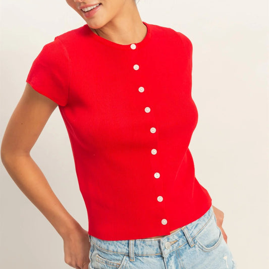 Woman wearing a red button-up shirt and light blue jeans against a plain background