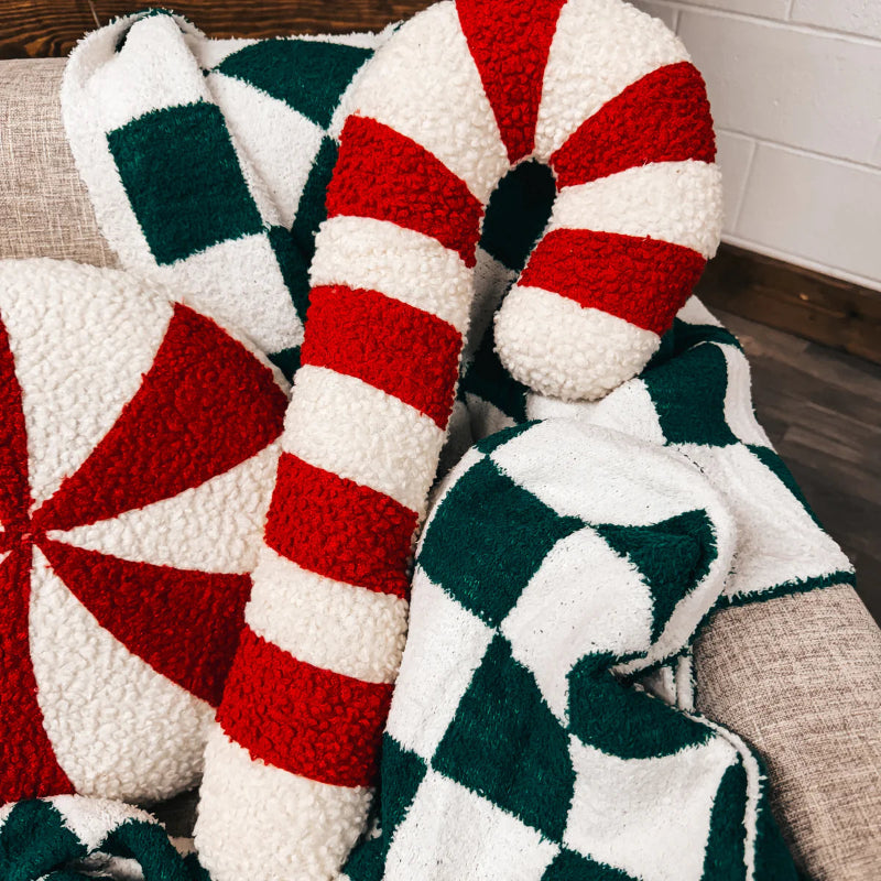 Knitted pillows with candy cane and peppermint designs on a couch.