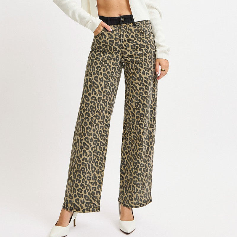 Woman wearing a white cardigan, black and white striped top, and leopard print pants on a white background