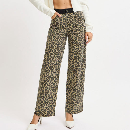 Woman wearing a white cardigan, black and white striped top, and leopard print pants on a white background