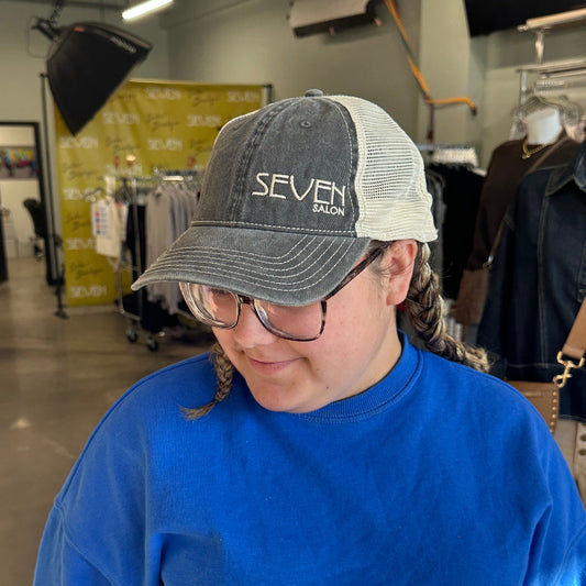 Person wearing a blue sweatshirt and cap in an indoor setting