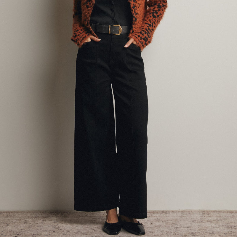 Woman wearing a leopard print cardigan over a black outfit against a plain background