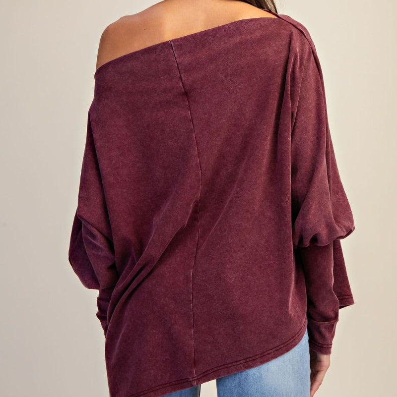 Maroon off-shoulder top worn by a person on a beige background