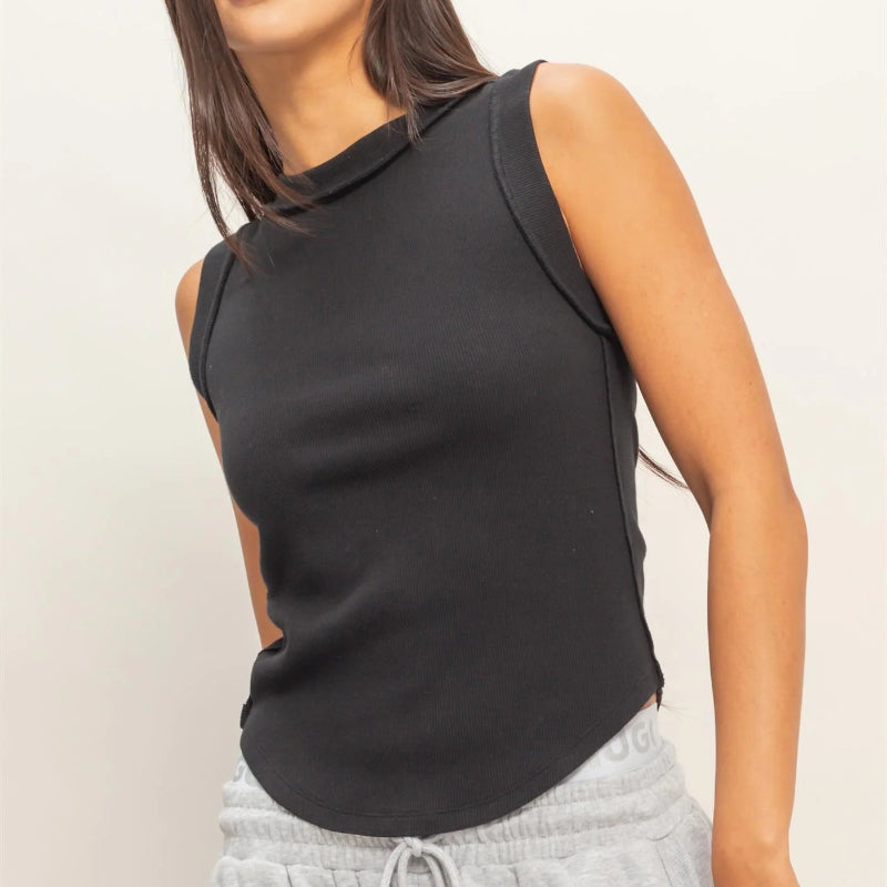 Woman wearing a black sleeveless top and gray pants on a plain background
