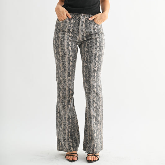 Woman wearing a black off-shoulder top and snake print pants on a white background